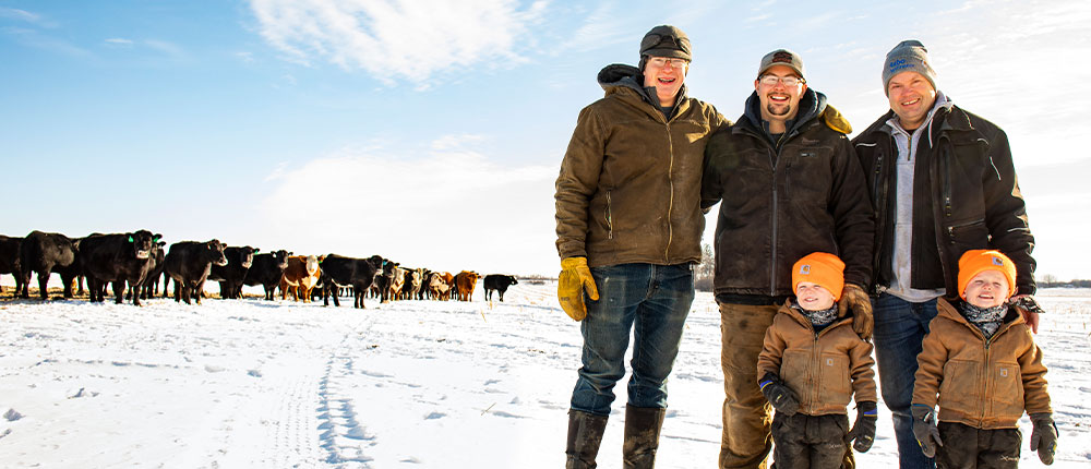 Richard Stadheim stands in a snow-covered cattle field with his sons, Garrett and Bennett, and Bennett’s young twin boys