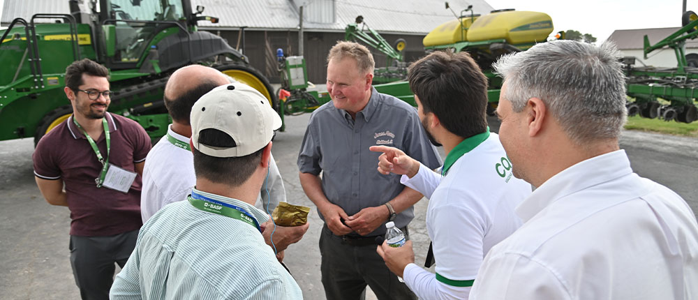 Group of men talking in front of a tractor and planter